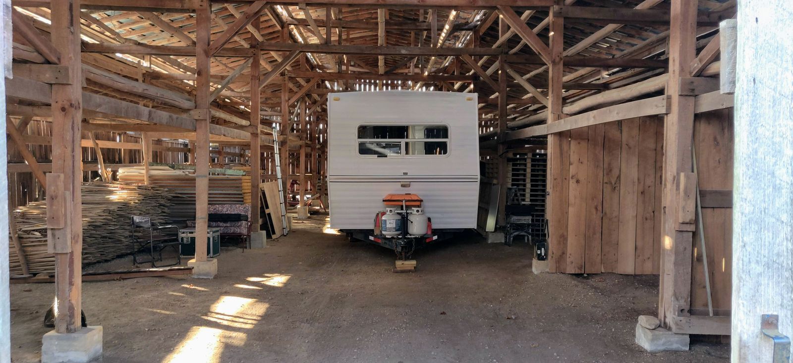 Inside the timber-frame barn, trailer and salvaged lumber stored